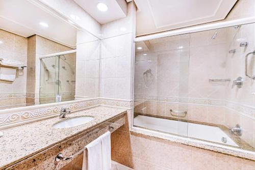 a bathroom with a sink and a shower and a tub at Hotel Euro Suite Campinas by Nacional Inn - Próximo ao Cambuí in Campinas