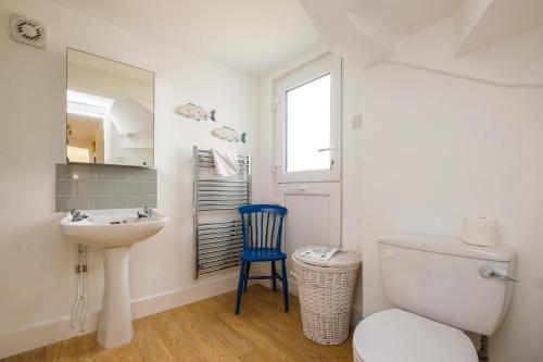 a bathroom with a sink and a toilet and a mirror at Shore Cote, Thorpeness in Thorpeness
