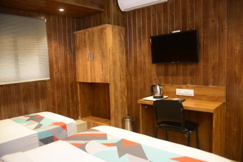 a bedroom with a bed and a desk and a television at Hotel Malad Inn opposite Malad Railway Station in Mumbai