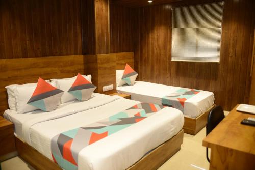 a bedroom with two beds and a table and a desk at Hotel Malad Inn opposite Malad Railway Station in Mumbai