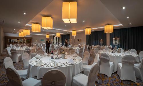 a banquet hall with white tables and white chairs at Maldron Hotel Belfast International Airport in Aldergrove