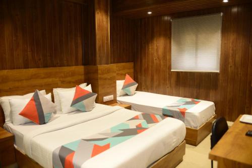 a bedroom with two beds and a table and a desk at Hotel Malad Inn opposite Malad Railway Station in Mumbai