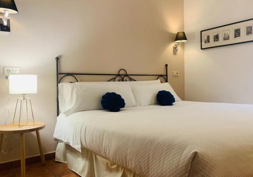 ein Schlafzimmer mit einem weißen Bett mit blauen Kissen in der Unterkunft Alda Hospedería De Los Reyes in Toledo