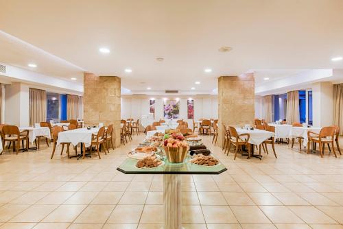 ein Esszimmer mit Tischen und Stühlen sowie einem Tisch mit Speisen in der Unterkunft Pearl Hotel in Rhodos (Stadt)