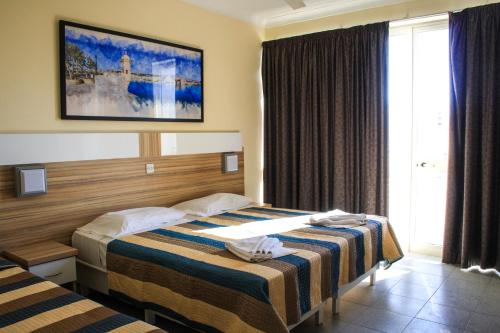 a hotel room with two beds and a window at Coral Hotel in St. Paul's Bay