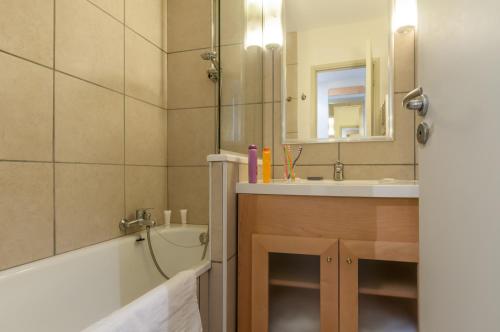 ein Badezimmer mit einer Badewanne, einem Waschbecken und einem Spiegel in der Unterkunft Résidence Pierre & Vacances La Forêt in Flaine