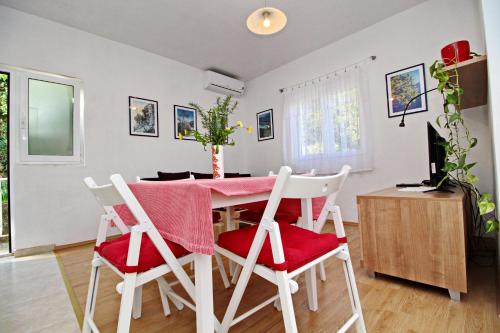 a kitchen and dining room with a pink table and chairs at Apartments Nodilo in Polače