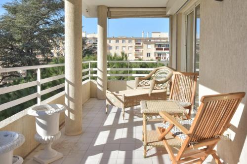 une terrasse couverte avec deux chaises et un canapé sur un balcon dans l'établissement 3-Br Apartment Sea View Swimming Pool, à Cannes