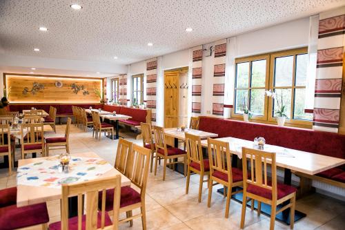 a restaurant with wooden tables and chairs and windows at Gutshof Colmberg in Colmberg