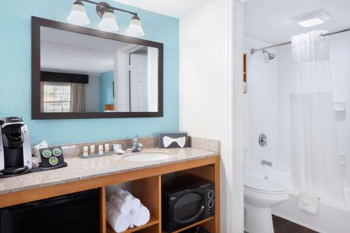 a bathroom with a sink and a toilet and a mirror at La Quinta Inn by Wyndham Cocoa Beach-Port Canaveral in Cocoa Beach