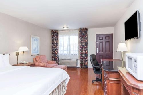 a hotel room with a bed and a desk at Days Inn & Suites by Wyndham Sunnyvale in Sunnyvale