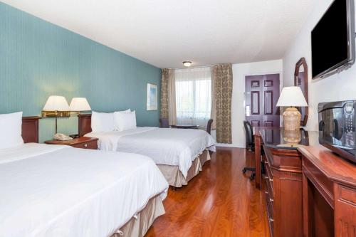 um quarto de hotel com duas camas e uma televisão de ecrã plano em Days Inn & Suites by Wyndham Sunnyvale em Sunnyvale