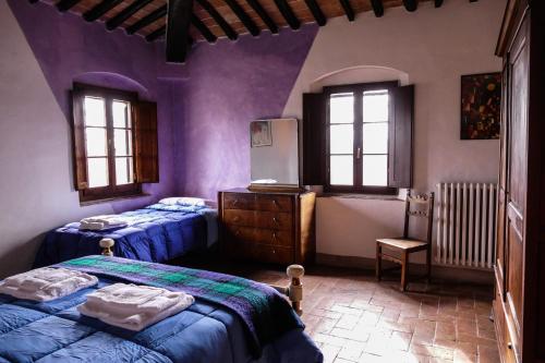2 letti in una camera con pareti e finestre viola di Bio-Agriturismo La Ginestra a San Casciano in Val di Pesa