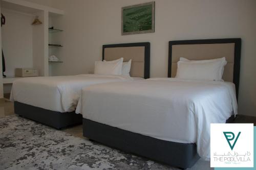 two beds in a bedroom with white sheets and pillows at THE POOL VILLA - TANUF in Nizwa