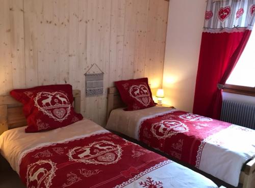- 2 lits dans une chambre avec des couvertures rouges et blanches dans l'établissement Locations de la cascade 4 personnes, à Besse-et-Saint-Anastaise