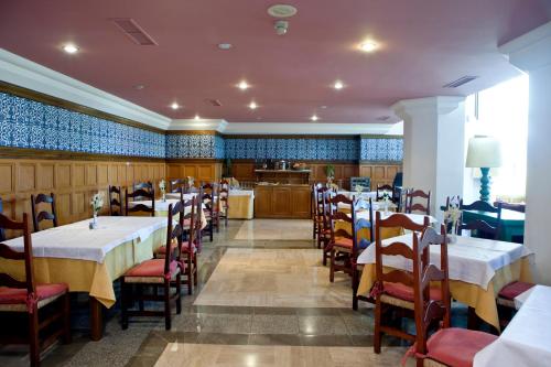 a restaurant with tables and chairs and a kitchen at Hotel Apartamentos Trevenque in Sierra Nevada