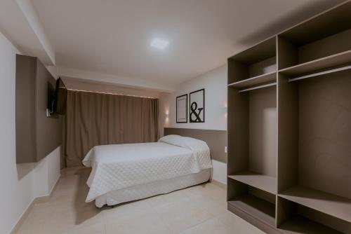 um quarto com uma cama, uma televisão e prateleiras em Guest Manaíra Apart Hotel em João Pessoa