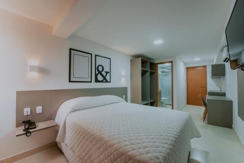 a bedroom with a large white bed and a bathroom at Guest Manaíra Apart Hotel in João Pessoa