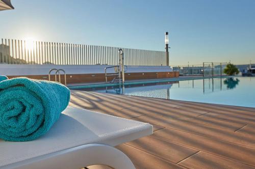 a towel sitting on a bench next to a pool at Calanova Sports Residence in Palma de Mallorca