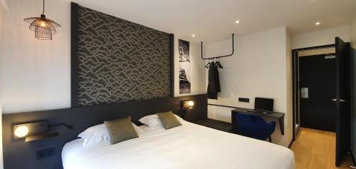 a bedroom with a white bed and a blue chair at The Originals Boutique, Hôtel La Chaussairie, Rennes Sud in Chartres-de-Bretagne