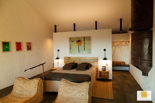 a bedroom with a bed and two wicker chairs at Casas do Amarelo in São Mateus