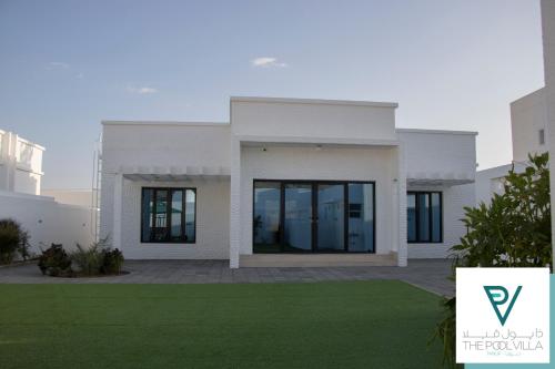 een wit huis met een gazon ervoor bij THE POOL VILLA - TANUF in Nizwa