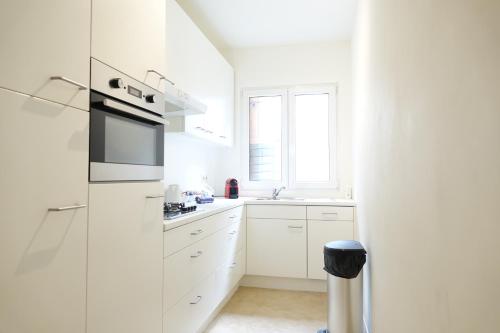a white kitchen with white cabinets and a window at The View - spacious 2 bdr appt in with view in Antwerp