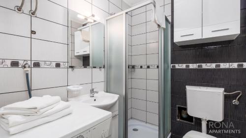 a white bathroom with a sink and a mirror at Rona Apartment Porat in Poreč