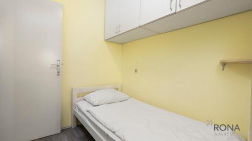 a small room with a bed in a room with yellow walls at Rona Apartment Porat in Poreč