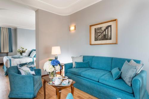 a living room with a blue couch and two chairs at Bettoja Hotel Mediterraneo in Rome