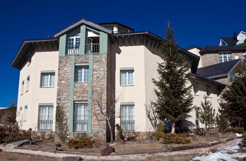 a large brick building with a tree in front of it at Hotel Apartamentos Trevenque in Sierra Nevada