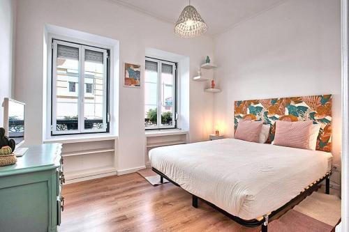 a bedroom with a large bed and two windows at Graça 4 in Lisbon