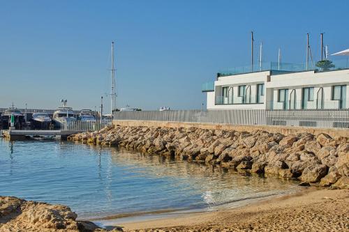 a marina with a stone wall and a building at Calanova Sports Residence in Palma de Mallorca