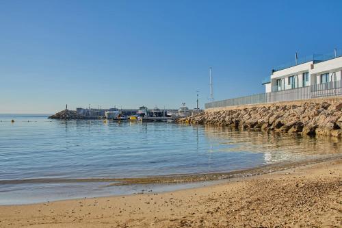 a beach with a building and the water at Calanova Sports Residence in Palma de Mallorca
