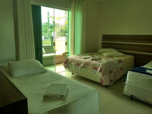 a hotel room with two beds and a window at Pousada Ilha do Itacolomi in Penha