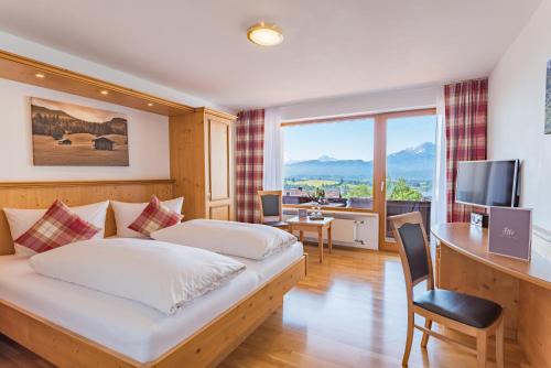 a hotel room with a bed and a desk and a television at Hartungs Hoteldorf in Füssen