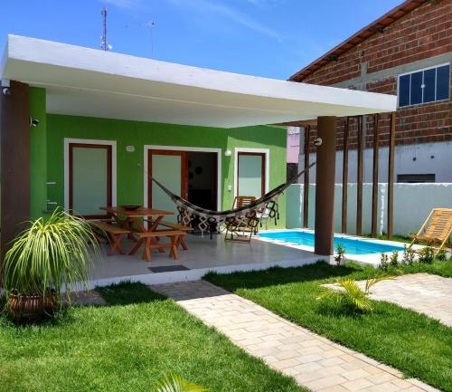 a house with a patio with a table and a hammock at GREEN HOUSE in Pipa