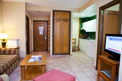 a living room with a couch and a table and a television at Hotel Apartamentos Trevenque in Sierra Nevada