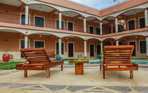 two wooden chairs sitting in front of a building at Hotel Los Frailes, Valladolid, Yucatán in Valladolid