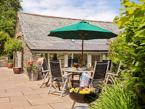 a patio with a table with a green umbrella at Garden House in Totnes