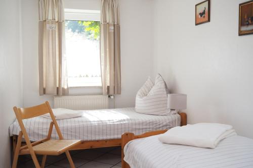 Zimmer mit 2 Betten, einem Stuhl und einem Fenster in der Unterkunft Ferienhof Tödter in Schneverdingen