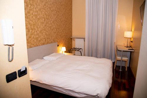 ゴルゴンゾーラにあるItalia 30の白いベッドとデスクが備わるホテルルームです。