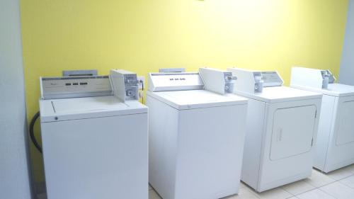 four washers and dryers are lined up against a wall at Magnolia Inn and Suites Olive Branch in Olive Branch
