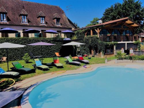 a resort with a swimming pool with chairs and umbrellas at Hôtel Bien-Être Aux Cyprès de Marquay in Marquay