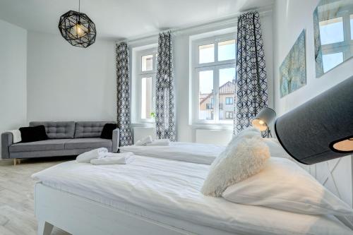 ソポトにあるDom & House Apartment Monte Cassino 21の白いベッドルーム(ベッド2台、ソファ付)