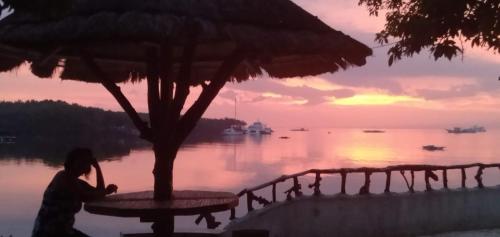 a person sitting on a table under an umbrella at Adayo Cove Resort in Siquijor