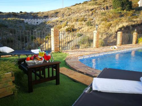 Una mesa con fruta al lado de una piscina. en Mi morada, en Mijas