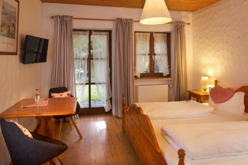 a bedroom with two beds and a desk and a table at Landgasthof Zum Alten Reichenbach in Nesselwang