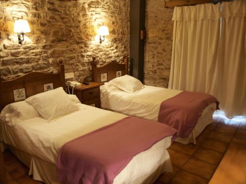 a bedroom with two beds and a stone wall at Hotel La Vega in Alcalá de la Selva