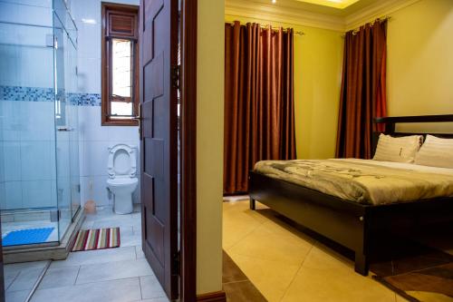 a bedroom with a bed and a shower and a toilet at Dina Apartments in Kampala